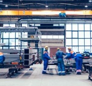 Large factory hall, blue-collar workers at work.