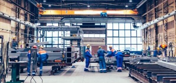 Large factory hall, blue-collar workers at work.