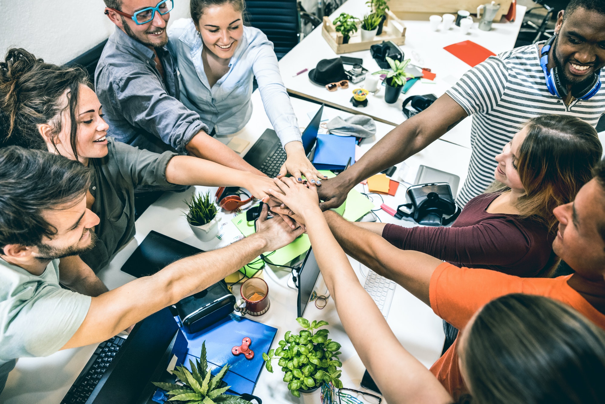 Young employee startup workers group stacking hands at urban studio