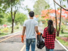 Men and women help each other to collect garbage.